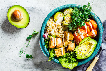 Buddha bowl with quinoa, tofu, avocado, sweet potato, brussels sprouts and tahini dressing, top view. Healthy vegan food concept. - obrazy, fototapety, plakaty
