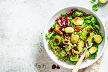  Fried brussels sprouts salad with quinoa, cranberries and nuts in white bowl, top view. Healthy vegan food concept. © vaaseenaa