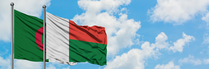 Algeria and Madagascar flag waving in the wind against white cloudy blue sky together. Diplomacy concept, international relations.