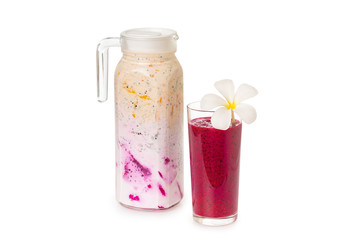 Jug of sweet colorful layered yougurt with fruits and berries and a glass of dragon fruit juice decorated with flower isolated at white background. Concept of detox and vegan healthy lifestyle.