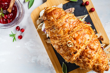 Croissant sandwich with duck meat, cream cheese and cranberry sauce on the board, top view.