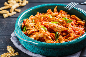 Soy vegan meat in tomato sauce in a blue dish on a dark background. Vegan food concept.