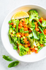 Steamed vegetables (broccoli, carrots, beans, peas, corn) in white plate, top view. Healthy diet food concept.