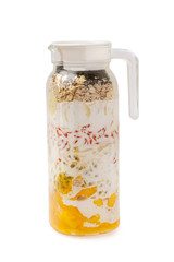  jug of homemade layered smoothie of mango, passion fruit, oats, chia seeds, banana, goji berries and coconut milk isolated at white background. Concept of vegan superfood and healthy lifestyle.