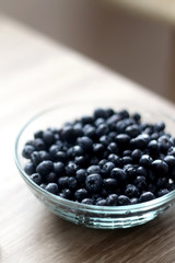 Bowl of blueberries on wooden table. Selective focus.