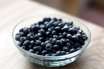 Bowl of blueberries on wooden table. Selective focus.