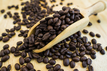 Coffee bean and wooden scoop on natural wood table with great texture and ambiance background for menu or cafe