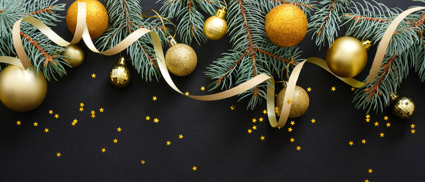 gold christmas balls with ribbon on a black background