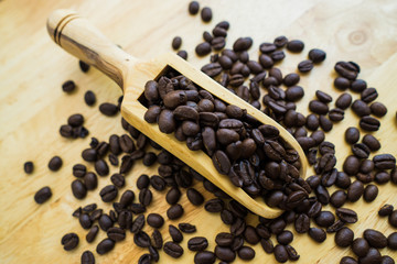 Coffee bean and wooden scoop on natural wood table with great texture and ambiance background for menu or cafe