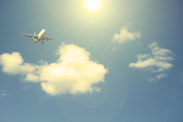 Airliner against the blue sky with white clouds. The sun shines.