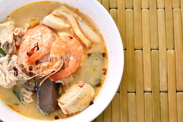 boiled shrimp and chicken with herb in Thai spicy tom yum soup on bowl