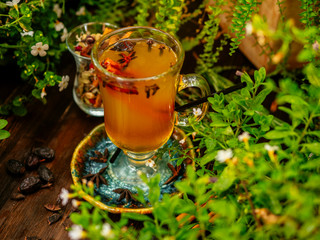 Hot mulled wine in a glass goblet with cinnamon sticks. Vegetation around