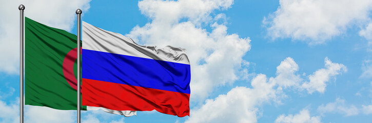 Algeria and Russia flag waving in the wind against white cloudy blue sky together. Diplomacy concept, international relations.