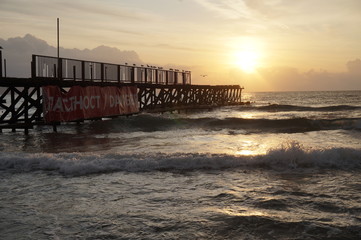 An old pier leaving in the sea leading to the rising sun in the morning, concept road leading to the light.