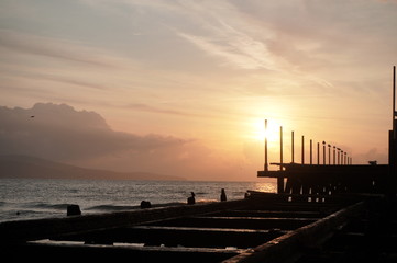 Obraz premium An old pier leaving in the sea leading to the rising sun in the morning, concept road leading to the light.