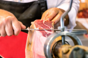 Butcher slicing slices of a spanish iberian serrano ham