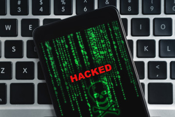 Closeup of hacked smartphone lying on laptop keyboard