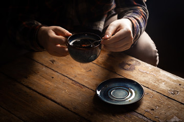 Closeup black americano coffee in blue cup in male hand, saucer with vintage tea spoon on...