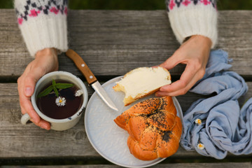 Scythe with poppy seeds, butter and tea. Baking with poppy seeds and coffee. The work of a baker. Poppy seed baking and pies.Bakery, cook together. Bun with butter on the nature in the forest. Picnic