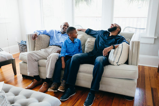 Grandfather, son, and grandson sitting together at home