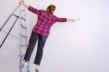 A woman paints the walls, falling from a stepladder. Problems with safety during repair work, copy space