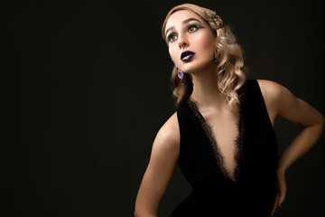 Fototapeta premium Beautiful girl with retro hairstyle and bright lilac makeup with golden glitters posing on dark background. copy space