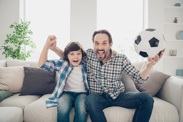 Portrait of two nice crazy ecstatic glad cheerful overjoyed guys dad and pre-teen son sitting on...