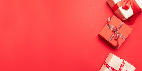 Creative gifts or presents boxes with gold bows and star confetti on red background top view. Flat lay composition for birthday, christmas or wedding.