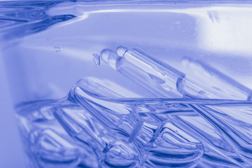 Glass medical ampoule vial for injection. Medicine is liquid sodium chloride with of aqueous solution in ampulla. Close up. Bottles ampule multicolor.