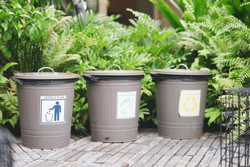 Waste separation. 3 classic trash cans in the public garden with label general waste, wet waste and recycle sign.