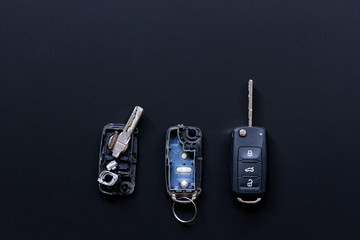 Broken or damaged remote key fob and new vehicle key on black dark grey background. Broken or damaged remote key fob of any vehicle car service.- Image