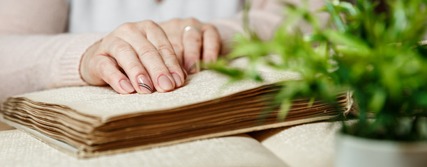 woman reading braille text on old book