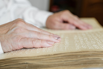woman reading braille text on old book