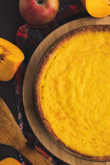 Pumpkin pie, apples, autumn leaves on a wooden table. Traditional homemade bake for Thanksgiving. Rustic style. Top view