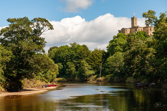 Rowing boats moored at the base of Warkworth Castle, Morpeth, Northumberland, UK on a sunny day
