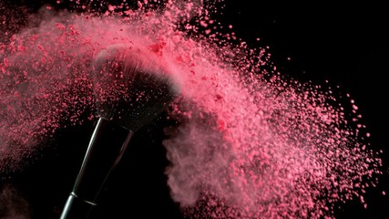 Super slow motion of makeup brush with falling pink powder, black background. Filmed on high speed cinema camera, 1000fps.