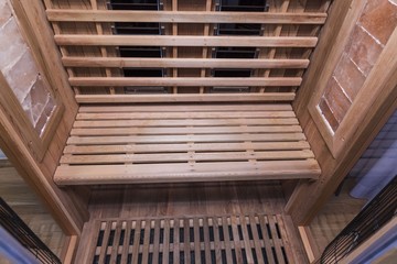 Obraz premium Infrared sauna interior close up view. Wooden walls and bench, ceramic heaters. Healthy lifestyle concept.
