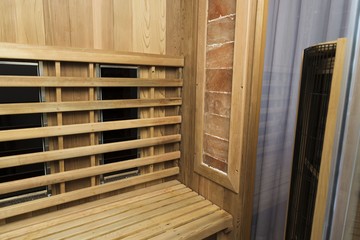 Infrared sauna interior close up view. Wooden walls and bench, ceramic heaters. Healthy lifestyle concept.