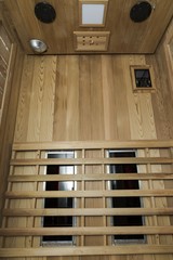 Infrared sauna interior close up view. Wooden walls and bench, ceramic heaters. Healthy lifestyle concept.