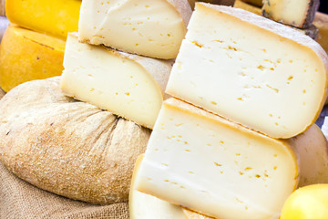 mix of various varieties of hard cheese on a wooden board. View from above.