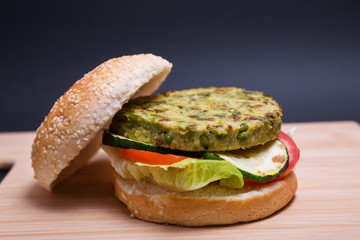 Hamburguesa vegana de guisantes y judías verdes con lechuga, tomate y calabacín en una table de...