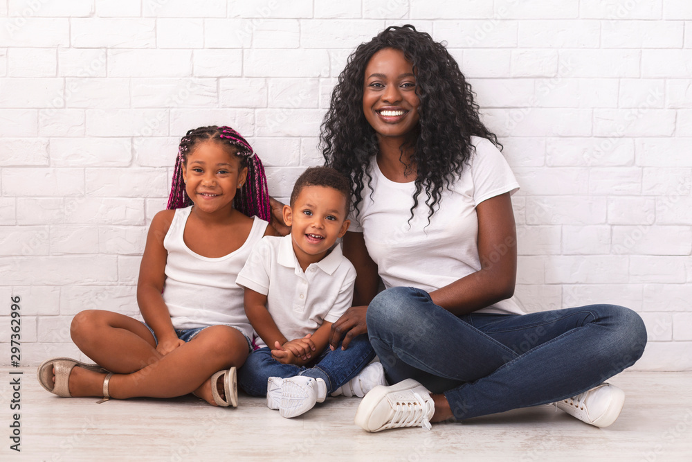 Wall mural young woman with daughter and son, sitting on floor together