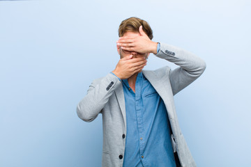 young businessman covering face with both hands saying no to the camera! refusing pictures or...