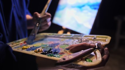 Artist copyist paint seascape with ship in ocean. Craftsman decorator draw as boat sail on blue sea with acrylic oil color. Draw finger brush palette.