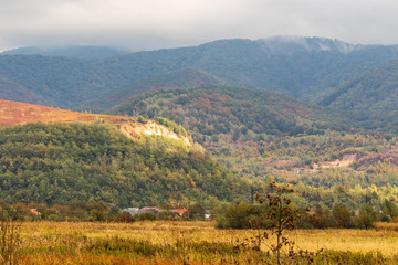 High mountains and blue cloudy sky. Several small houses.    Autumn landscape. Panoramic view.