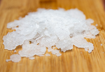 Natural sea salt on wooden background. Anthos sea salt. Flakes of natural sea salt. Crystals of sea salt.