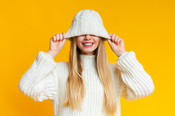 Smiling woman pulling down white woollen hat