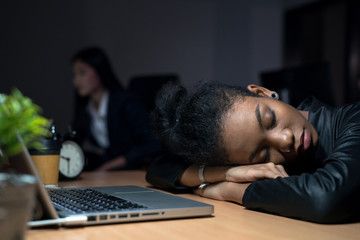 African businesswoman falls asleep because she is tired of working overtime in the office to...