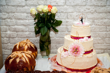 White wedding cake with flowers and special ceremony bread or loaf. Wedding concept. Closeup.