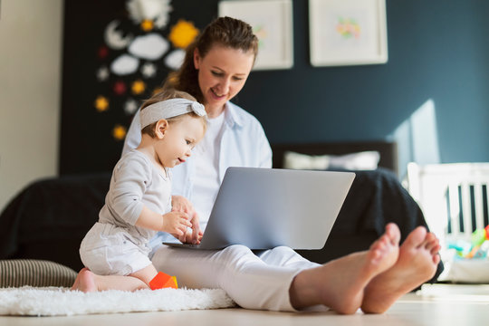 Young mother developing skills of her child with digital tools, watching educating cartoons and programs for kids online.
